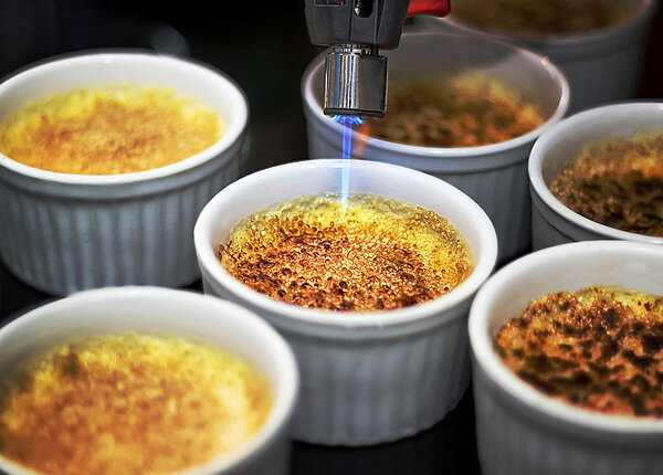 Crème brûlée Crème brûlée wird mit Bunsenbrenner flambiert