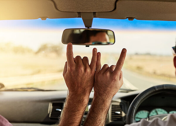 Festival-Anreise Zwei Freunde im Auto machen Handzeichen