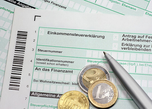 Außergewöhnliche Belastungen in der Steuererklärung Einkommensteuererklärung mit Münzen und Stift