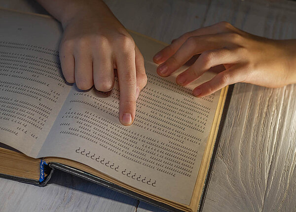 Legasthenie: LRS-Symptome, Definition, Hilfen und Tipps. Welche Tests auf LRS gibt es? Ein Kind liest ein Buch und folgt den Buchstaben und Zeilen mit dem Finger. Aber alle Buchstaben sind Fragezeichen.