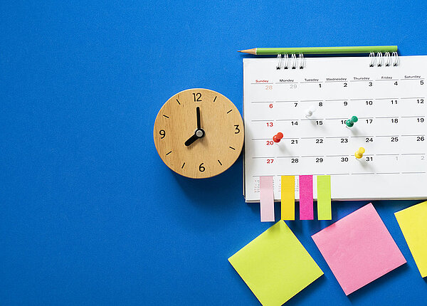 Zeitmanagement-Strategien Nahaufnahme des Kalenders auf blauem Hintergrund mit Pins und Bleistift, der obendrauf liegt