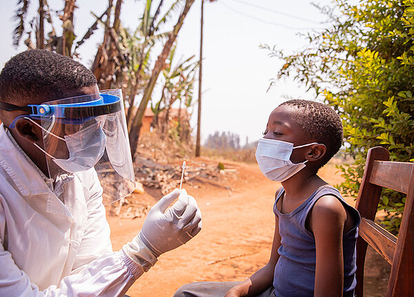 Ebola-Ausbruch Ein Arzt hält einen Tupfer in der Hand. Er trägt eine Maske und das Kind, dass ihm gegenüber sitzt, trägt einen Mundschutz