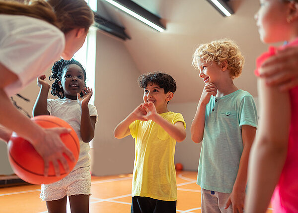 Zusammenhang Bewegung und psychische Gesundheit bei Kindern Mädchen und Jungen mit Lehrerin in Sporthalle
