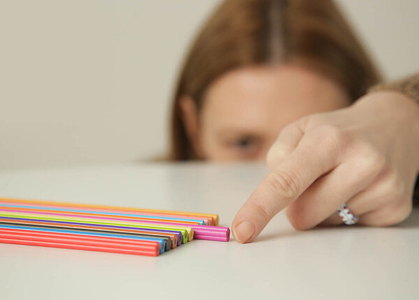 Zwangsstörung: Formen und Ursachen Eine Frau hat Stifte sortiert und verschiebt gerade den letzten so, dass er exakt auf einer Höhe mit den anderen liegt.