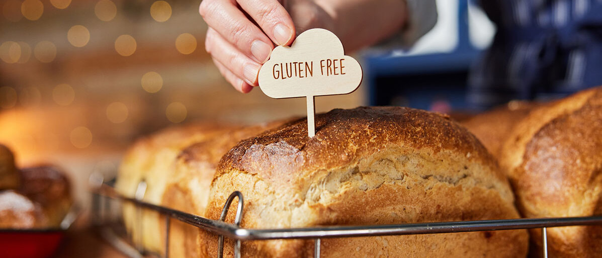 In einer Bäckerei wird ein Holz-Spicker mit der Aufschrift „Gluten Free“ in einen Laib Brot gesteckt.