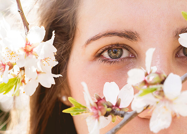 Nahaufnahme gerötete Augen einer Frau zwischen Kirschblüten