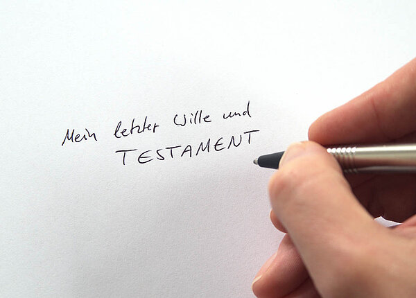 Sorgerecht für Kinder im Testament regeln: Miteiner Sorgerechtsverfügung den Vormund für Minderjährige als Vorsorge benennen. Jemand schreibt auf ein weißes Papier: Mein letzter Wille und Testament