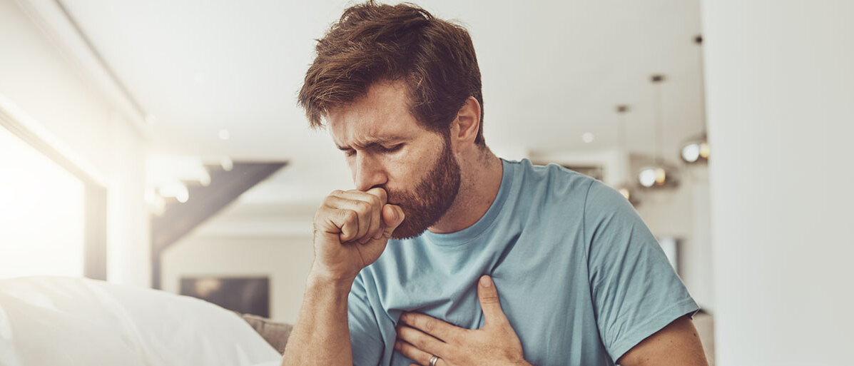 Atemwegsinfektionen Hustender Mann fasst sich an die Brust