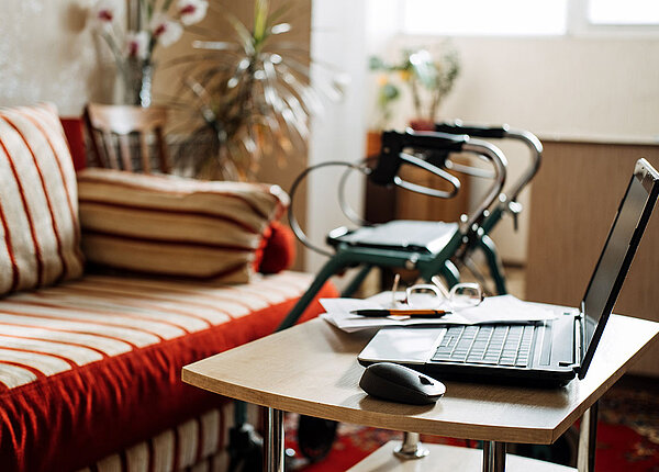 StĂŒrze mit Rollator vermeiden Wohnzimmer mit Sofa, Couchtisch und Laptop, im Hintergrund ein Rollator