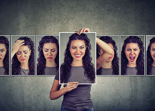 Eine Frau zeigt mehrere Fotos ihres Gesichts, jeweils mit einer anderen Emotion.