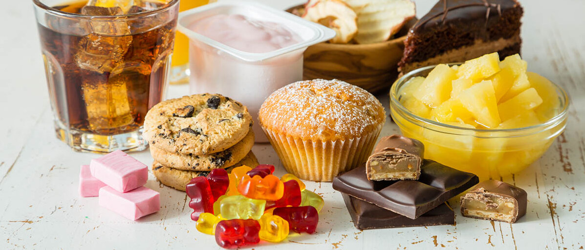 Zuckerhaltige Lebensmittel: Cola, Orangensaft, Fruchtjoghurt, Konserven-Ananas, Torte, Kekse, Muffin, Schokolade, Apfelchips, Gummibärchen und drei Kaubonbons