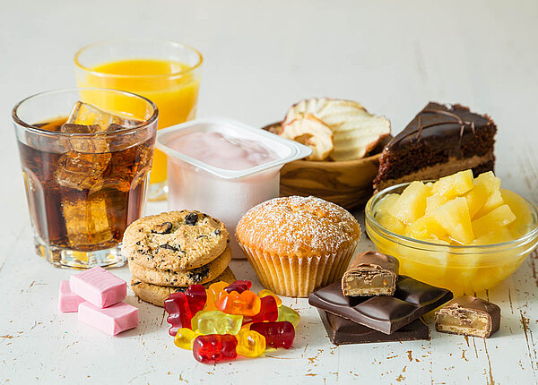 Zuckerhaltige Lebensmittel: Cola, Orangensaft, Fruchtjoghurt, Konserven-Ananas, Torte, Kekse, Muffin, Schokolade, Apfelchips, Gummibärchen und drei Kaubonbons