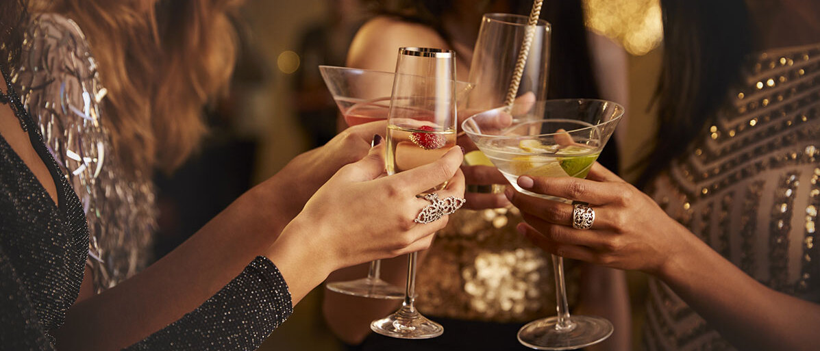 Vier Frauen stoßen auf einer Party mit verschiedenen alkoholischen Getränken an