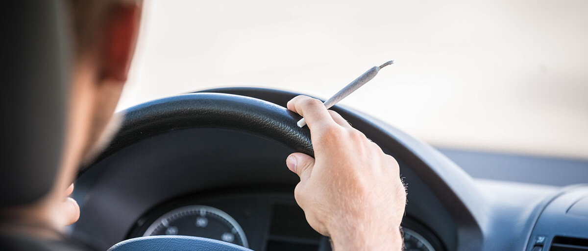 Cannabis und Alkohol im Straßenverkehr Mann mit Joint am Steuer