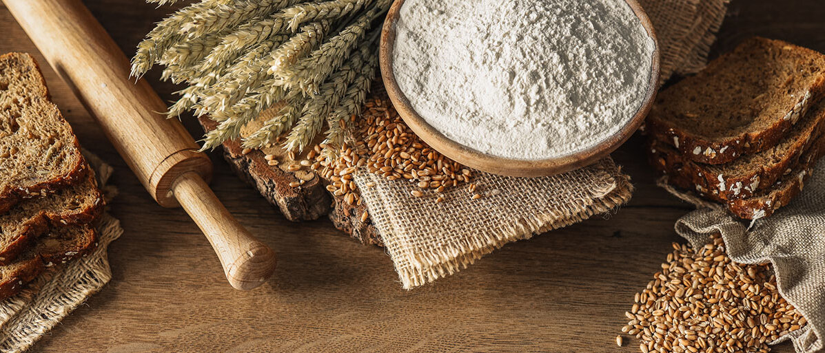 Alte Getreidesorten im Trend Brot, Getreide, Ähren und Mehl auf einem dunklen Holzgrund