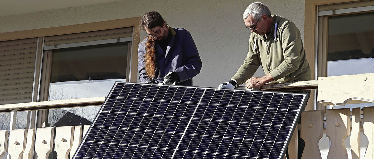 Zwei Männer montieren ein Photovoltaik-Modul an einem Balkon
