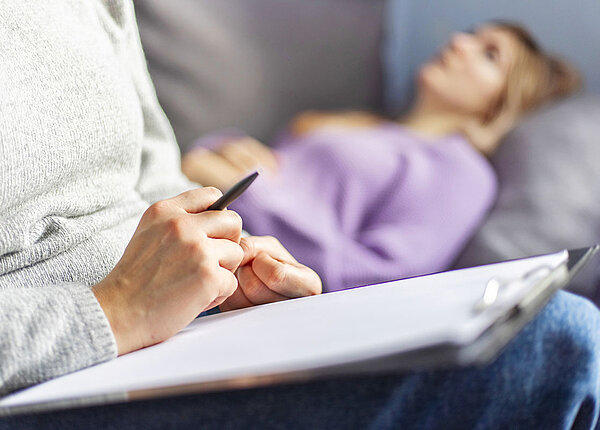 Nebenwirkungen der Psychotherapie Frau liegt auf dem Sofa und spricht mit Psychotherapeutin
