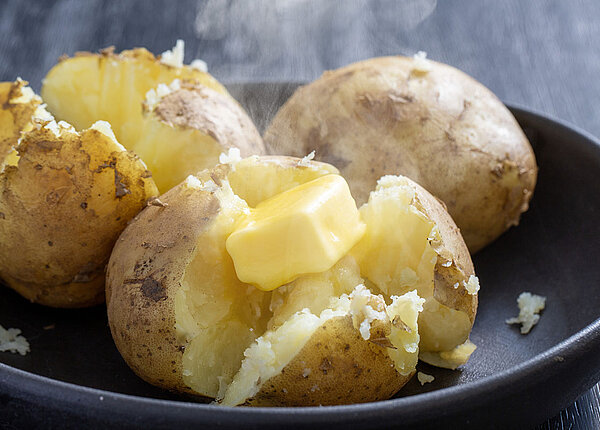 drei aufgeschnittene Kartoffeln mit Butter 