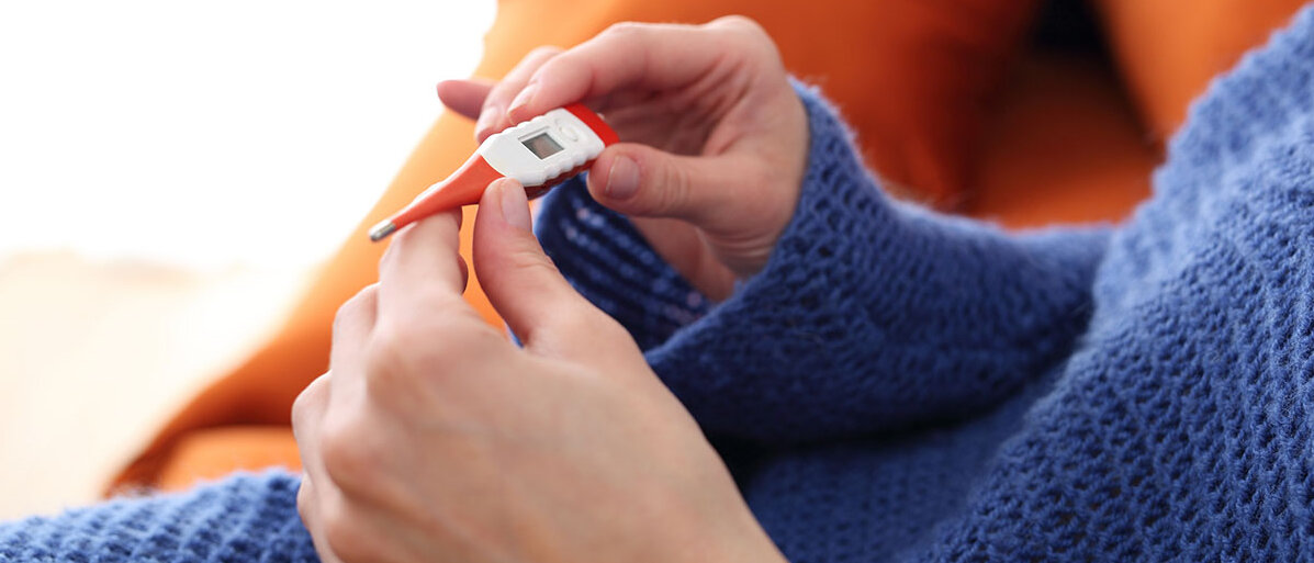 Nahaufnahme: Frau hält Fieberthermometer in der Hand 