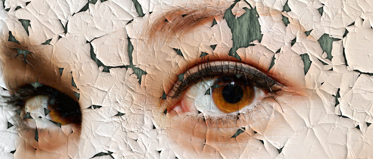 Eine Plakatwand zeigt die Augenpartie einer Frau. Die Farbe blättert spröde ab.