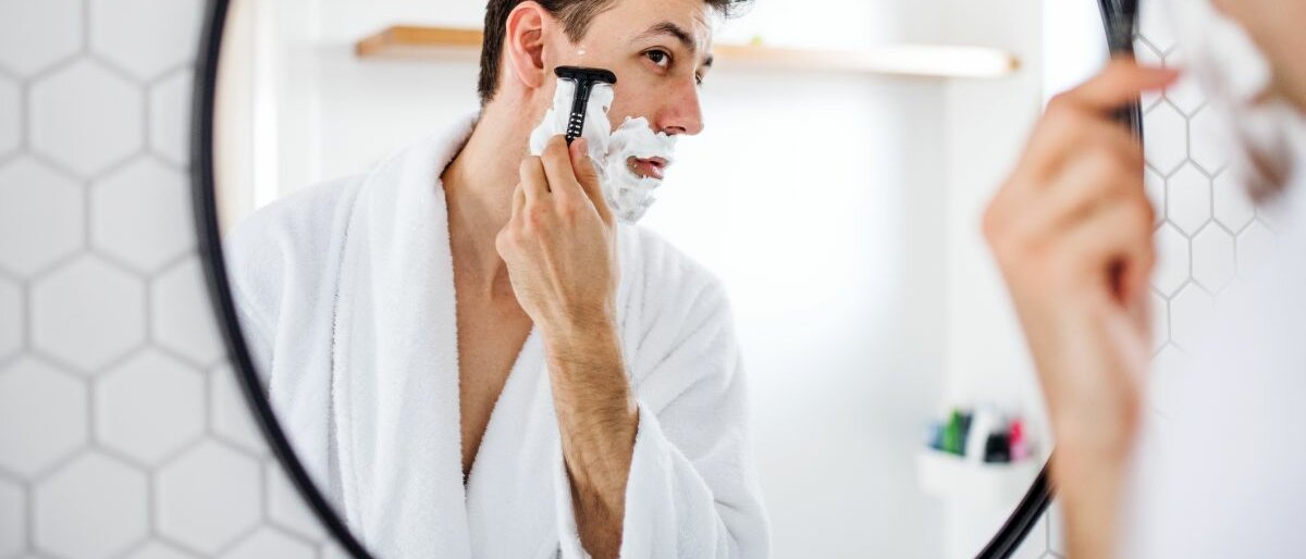 Ein Mann rasiert sich im Gesicht.