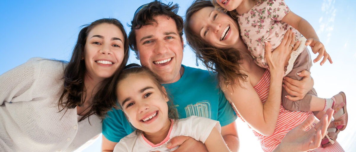 Eine große Familie strahlt für Gruppenbild in die Kamera