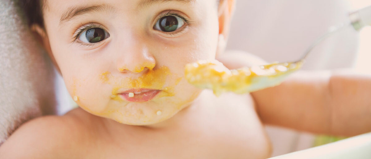 Ein Baby ist nach dem Brei-essen ganz verschmiert im Gesicht