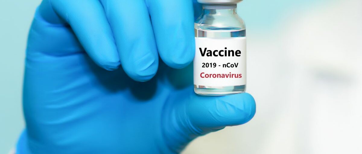 Eine Hand mit blauen Gummihandschuhen hält den Corona-Impfstoff in der Hand.