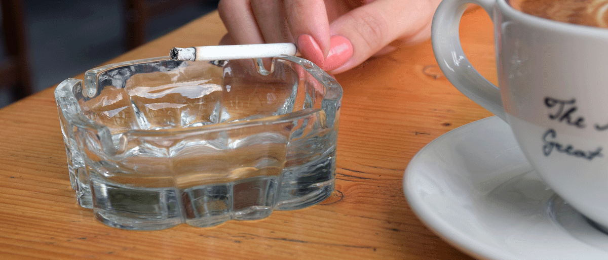 Rauchende Frau bei einer Tasse Cappuccino