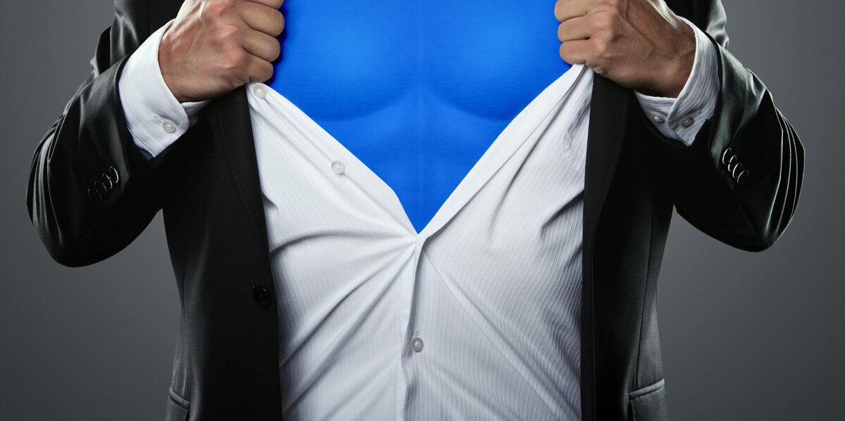 Ein Mann reißt sich sein Hemd auf, untendrunter ein Superhelden-Outfit