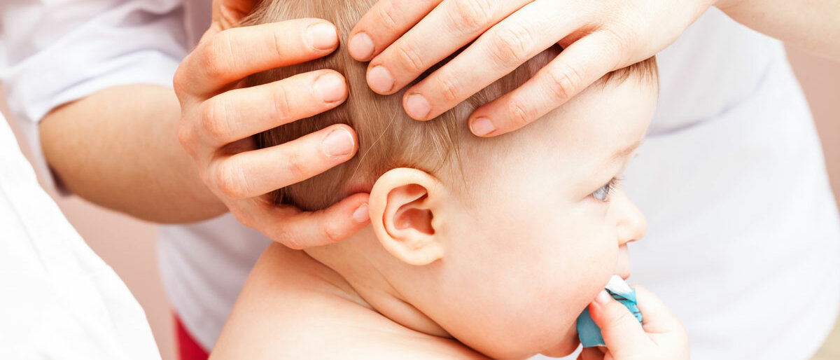 Ein Baby bekommt den Kopf untersucht.