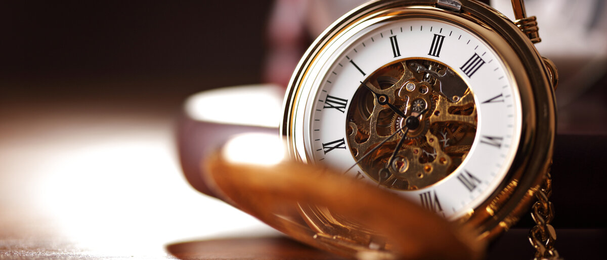 Auf einer aufgeklappten Taschenuhr mit sichtbarem Uhrwerk ist es ungefähr Viertel vor eins.