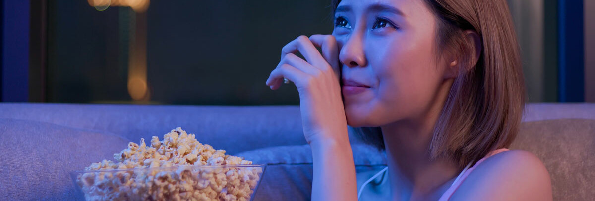 Eine Frau mit Popcorn-Schüssel auf dem Schoß weint