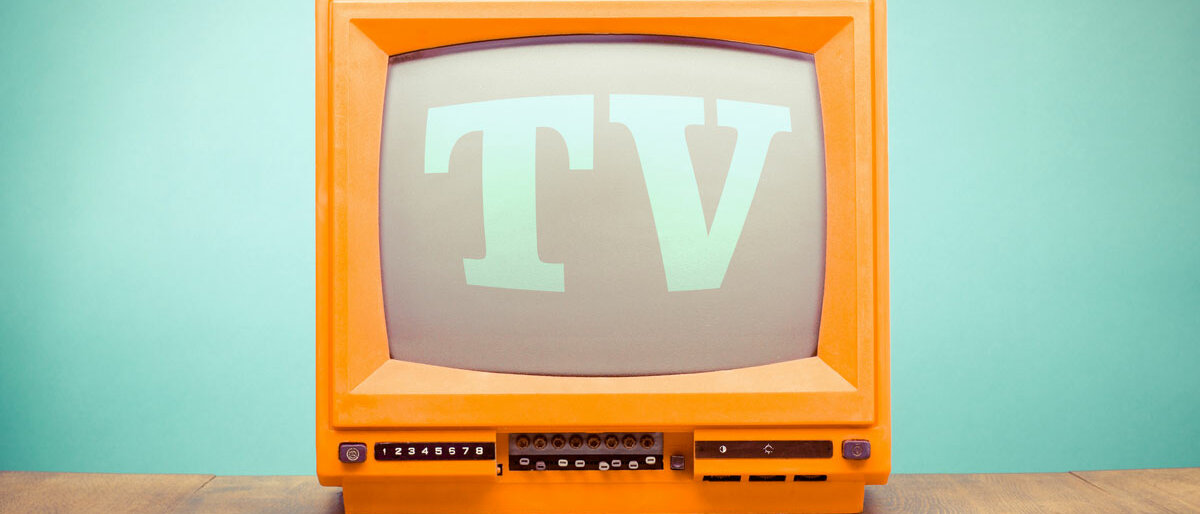 Ein alter Röhrenfernseher in orange, auf dem TV steht
