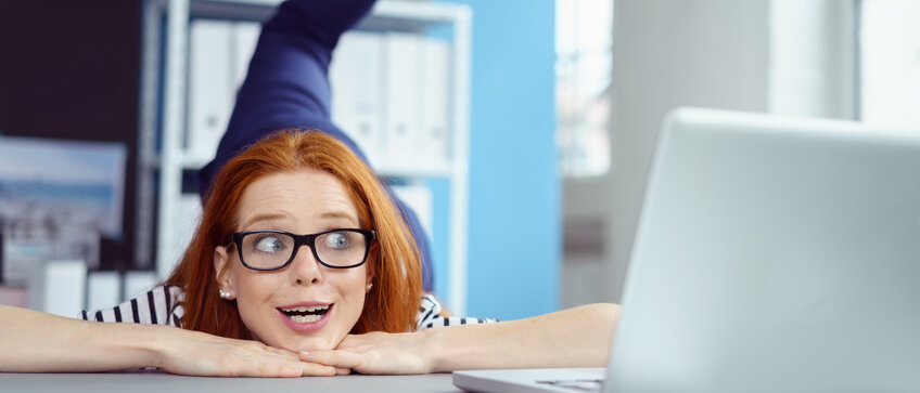 Frau hebt bein am Schreibtisch nach hinten oben