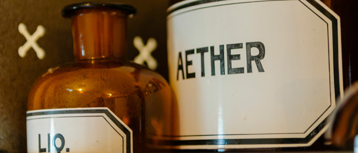 Zwei alte Braunglasflaschen stehen nebeneinander, eines ist mit "Aether" beschriftet.